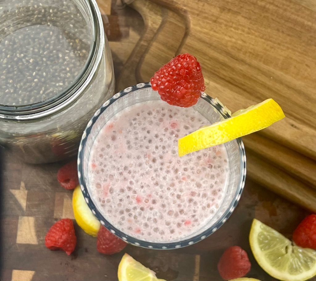 Top view of chia seed water with lemon and raspberries on a wooden board
