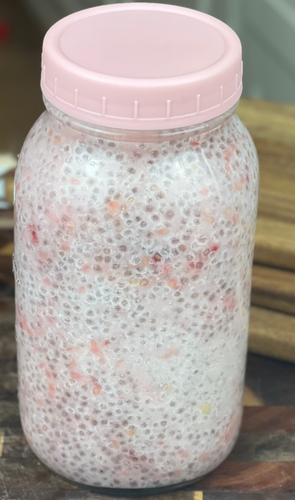 Jar of chia seed water with lemon and raspberries stored in the refrigerator