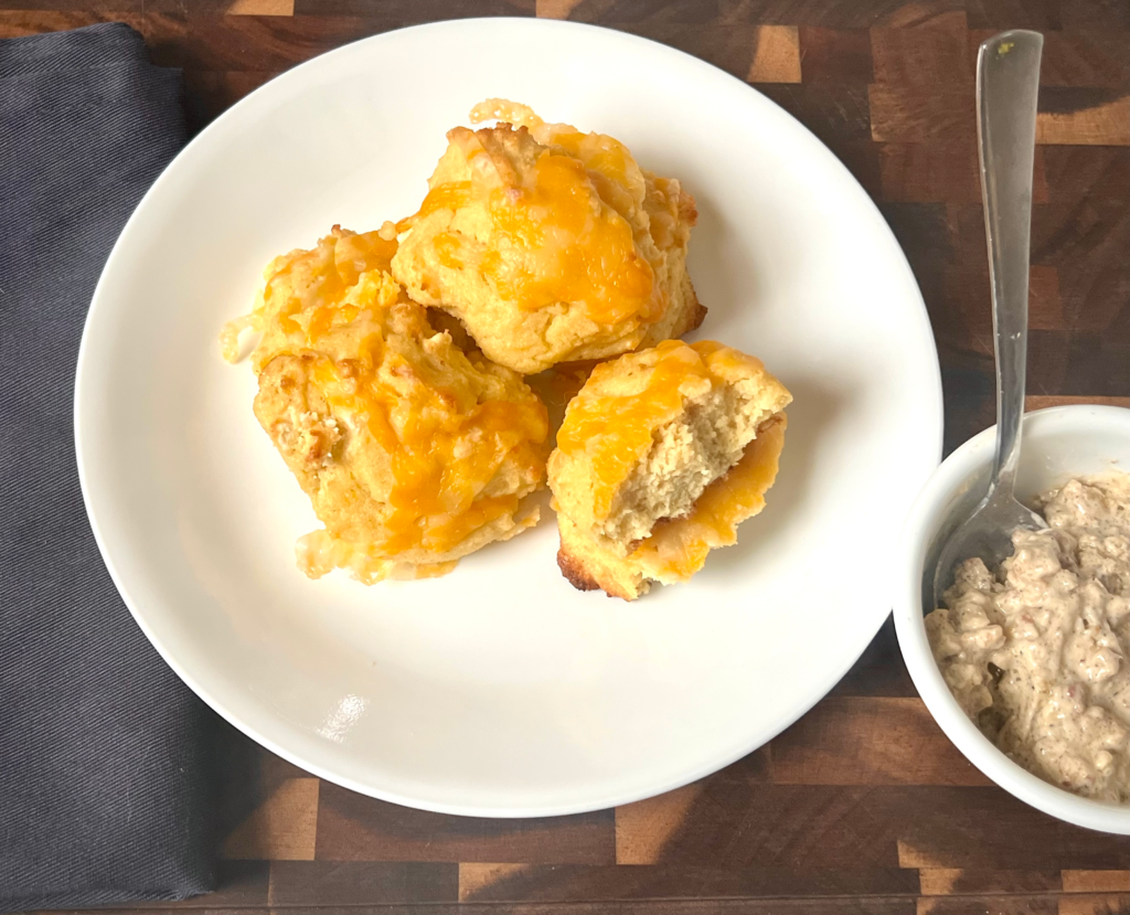 Freshly baked keto cheesy biscuits topped with melted cheddar cheese