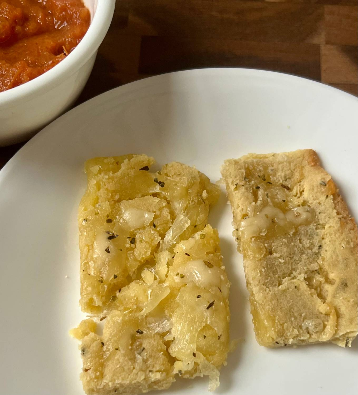 Keto cheesy bread sticks served with homemade marinara sauce on a white plate