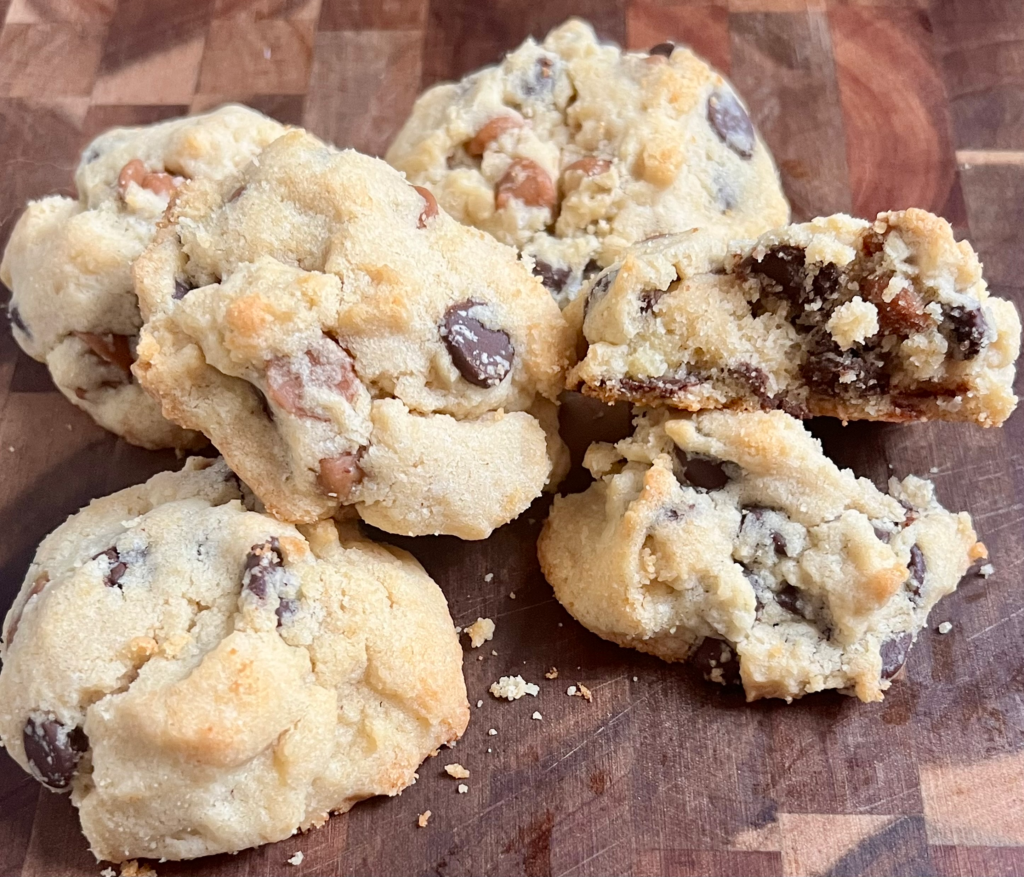 Keto peanut butter chocolate chip cookies with a soft, broken center on a wooden cutting board