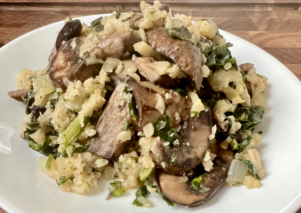 Close up of spinach mushroom cauliflower rice with sautéed mushrooms, onions, and parmesan cheese.