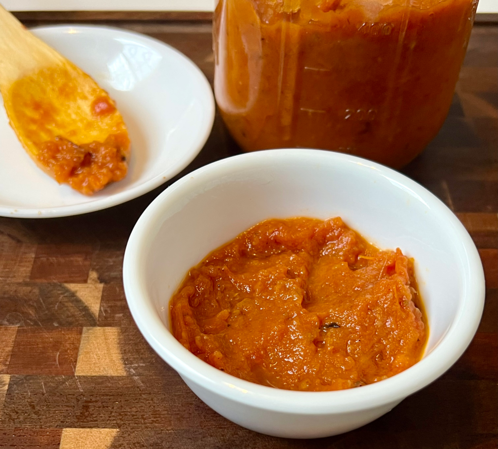 Homemade roasted tomato pasta sauce in a white bowl with a mason jar in the background