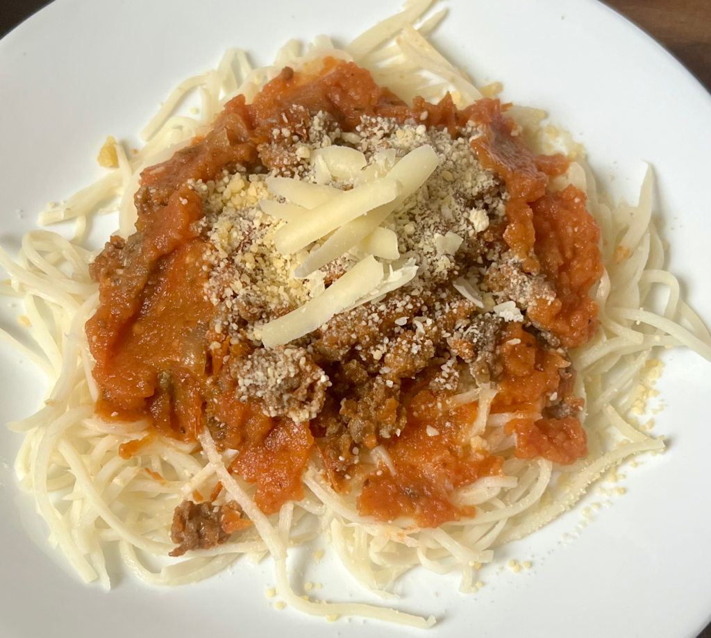 Keto spaghetti with homemade meat sauce and parmesan cheese on a white plate