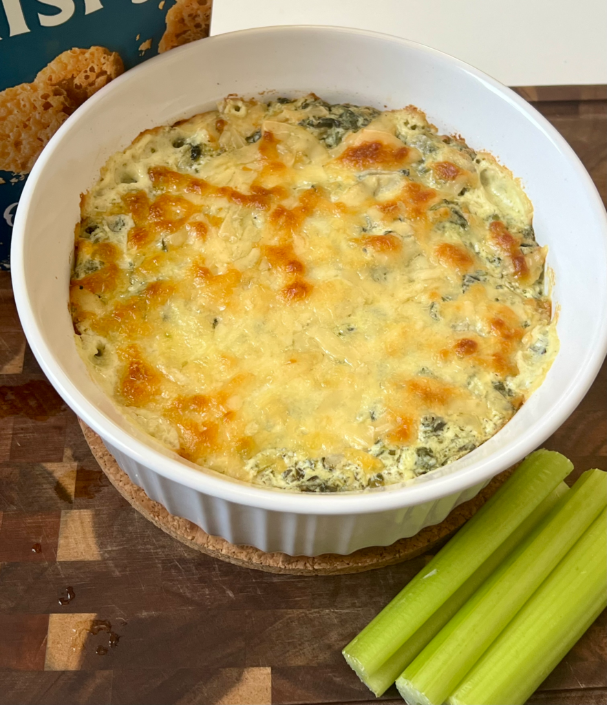 Freshly baked spinach artichoke dip served with celery sticks