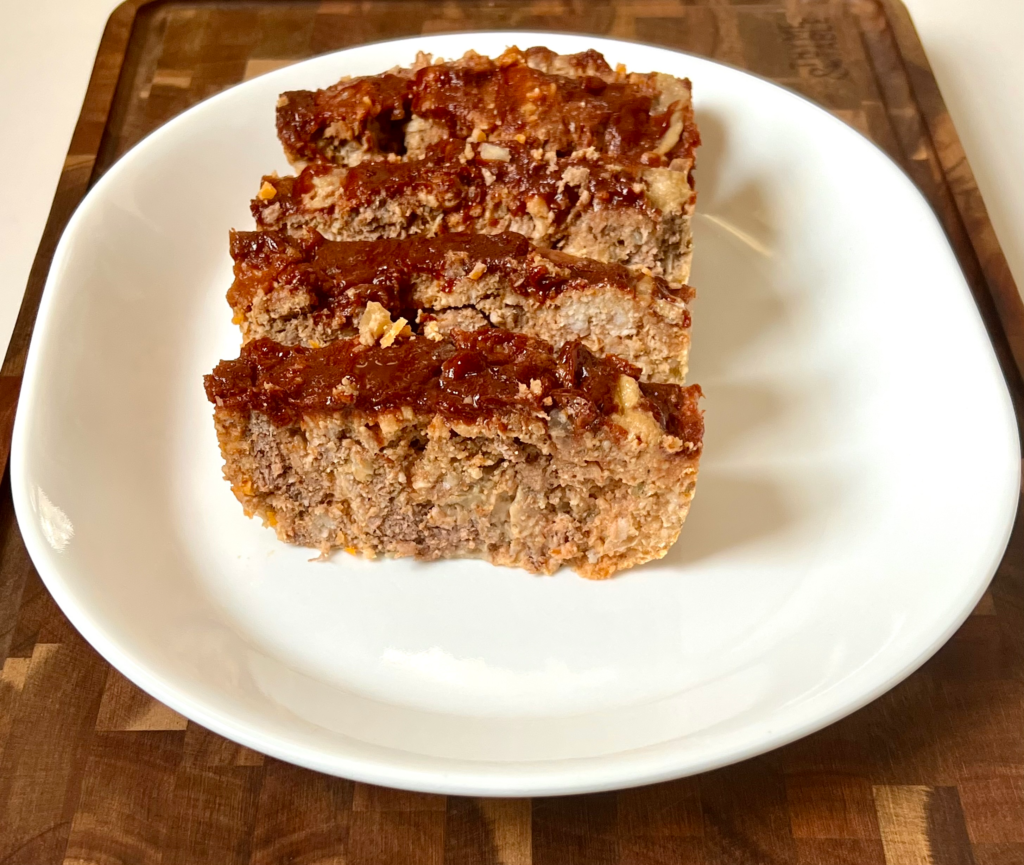 Juicy keto meatloaf topped with a caramelized low carb ketchup glaze sliced and served on a plate