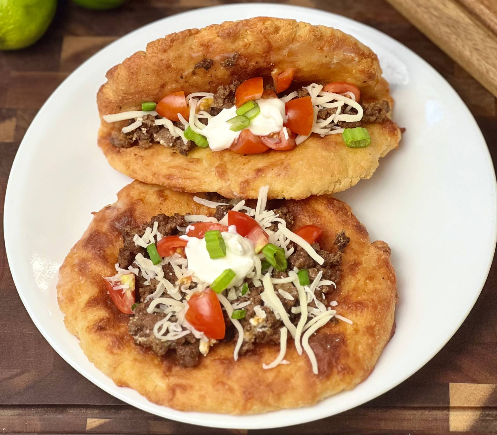 Keto beef chalupas made with mozzarella almond flour shells filled with seasoned ground beef and fresh toppings on a wooden board