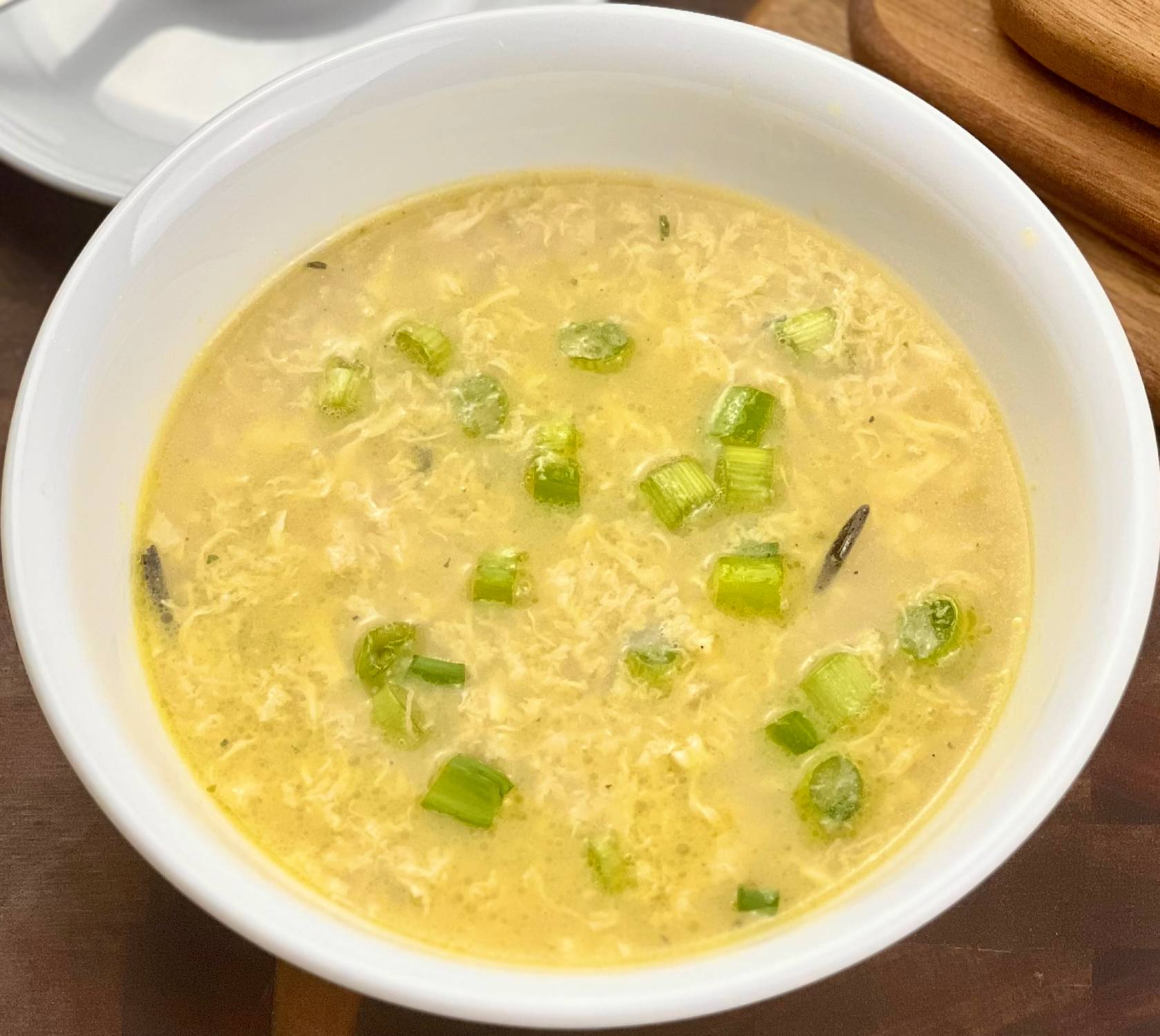 Keto egg drop soup served in a white bowl with silky egg ribbons and sliced green onions.