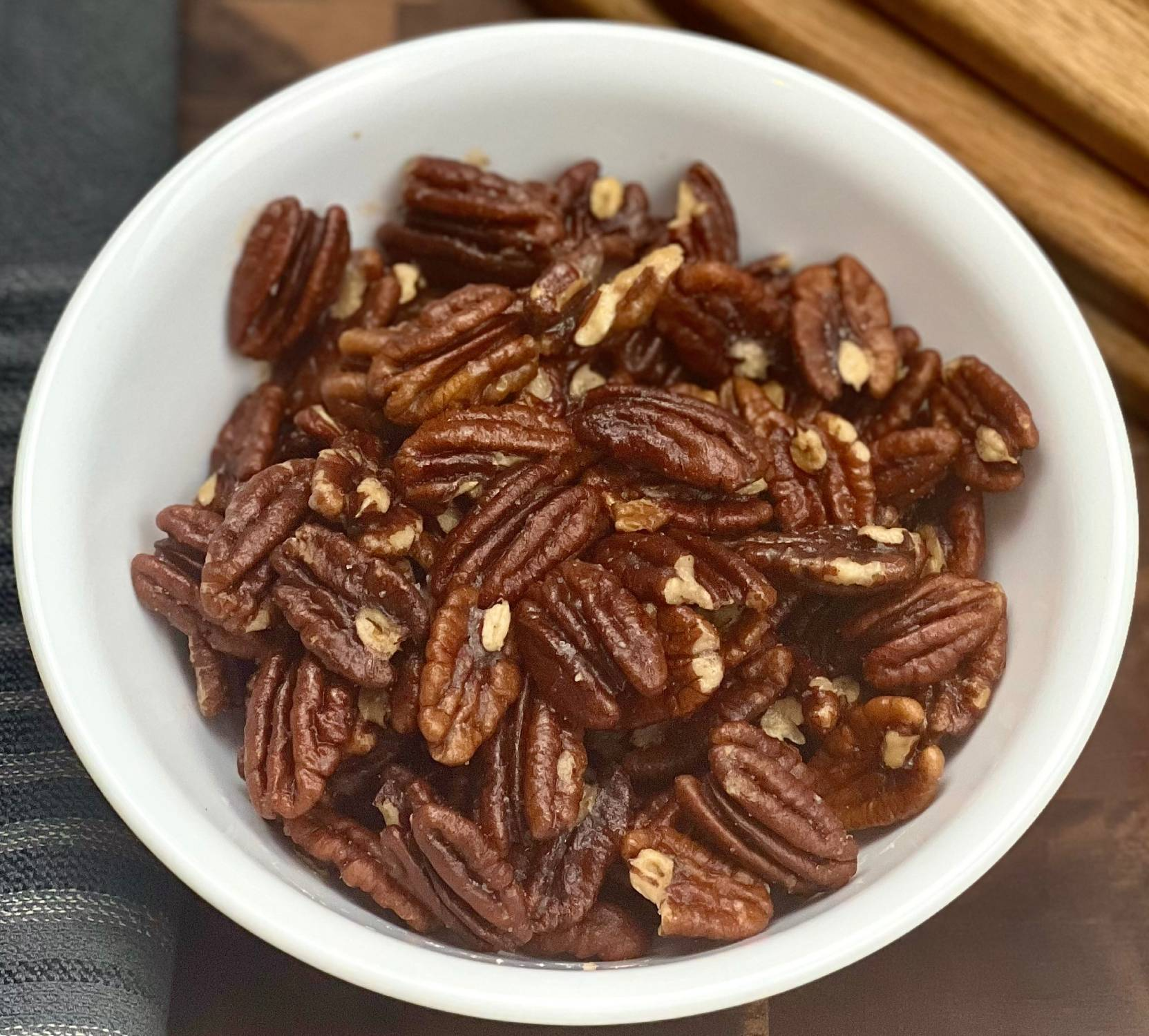 Buttery keto roasted pecans in a white bowl, slow roasted with salt for a simple low carb snack.