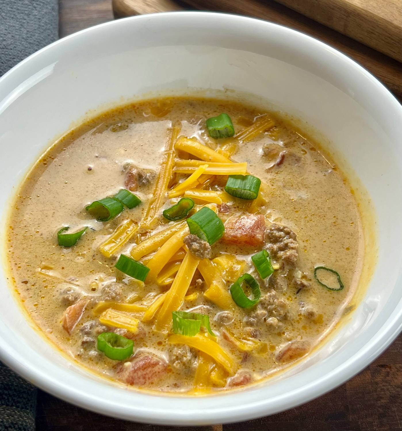 Keto taco soup topped with shredded cheese and green onions in a bowl